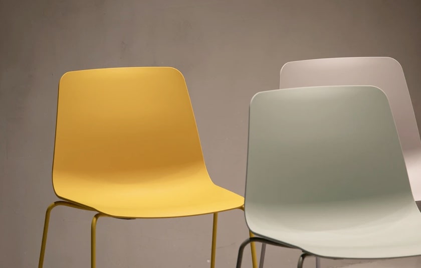 image of a yellow chair, gray chair, and a white chair in a light brown background