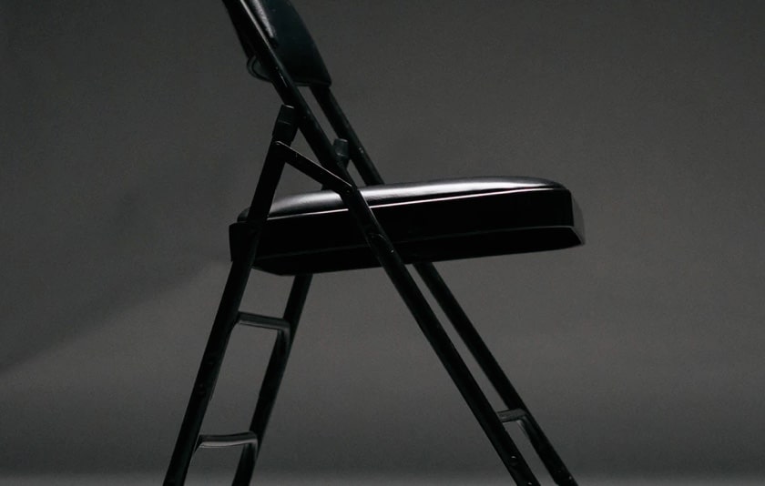 image of a black folding chair in a gray background